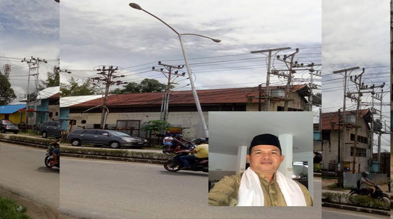 Ali Akbar dan Tiang PJU berada di depan Pos Lantas Nanga Pinoh yang miring dan nyaris tumbang