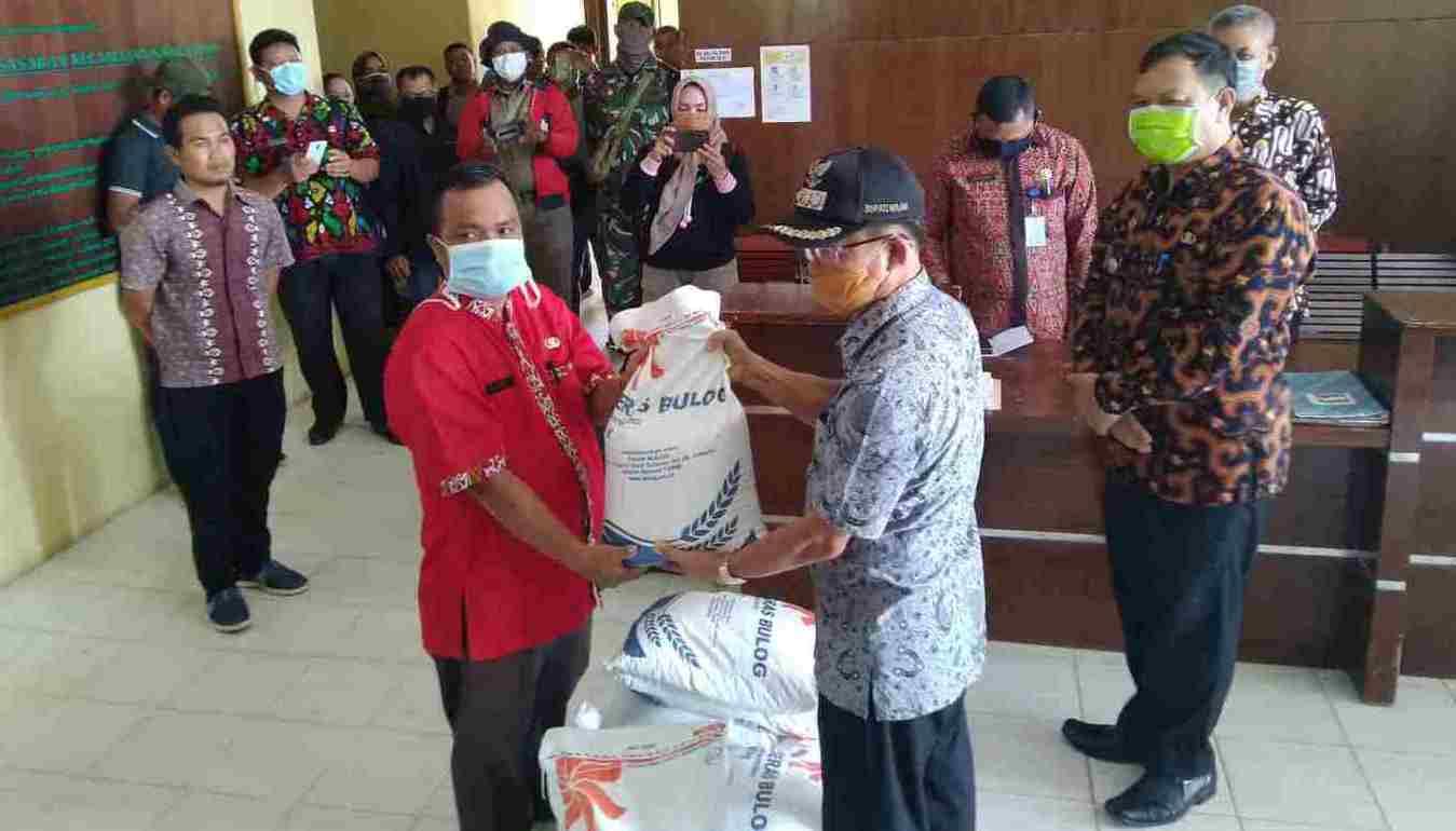 Bupati Melawi saat menyerahkan bantuan beras secara simbolis ke salah satu perwakilan desa. (ist)