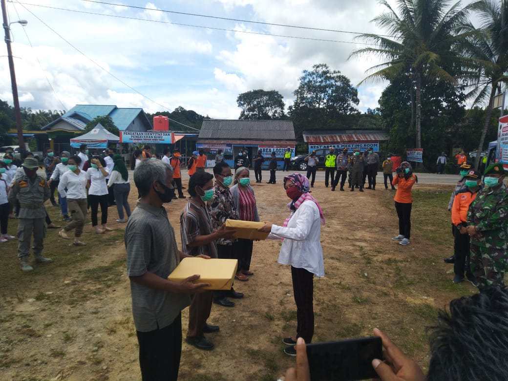 Pj Sekda Melawi menyerahkan bingkisan pada masyrakat Batu Nanta yang membantu berjalannya Posko Terpadu Covid di Perbatasan Sintang-Melawi. (Ist) 