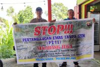 Seorang anggota Polisi bersama seorang warga saat membentangkan spanduk Stop PETI. (Ist)