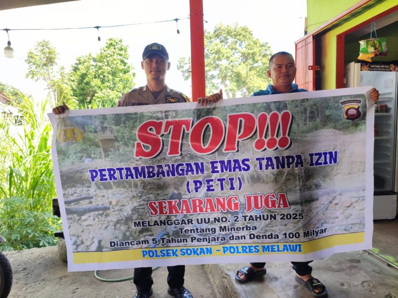 Seorang anggota Polisi bersama seorang warga saat membentangkan spanduk Stop PETI. (Ist)